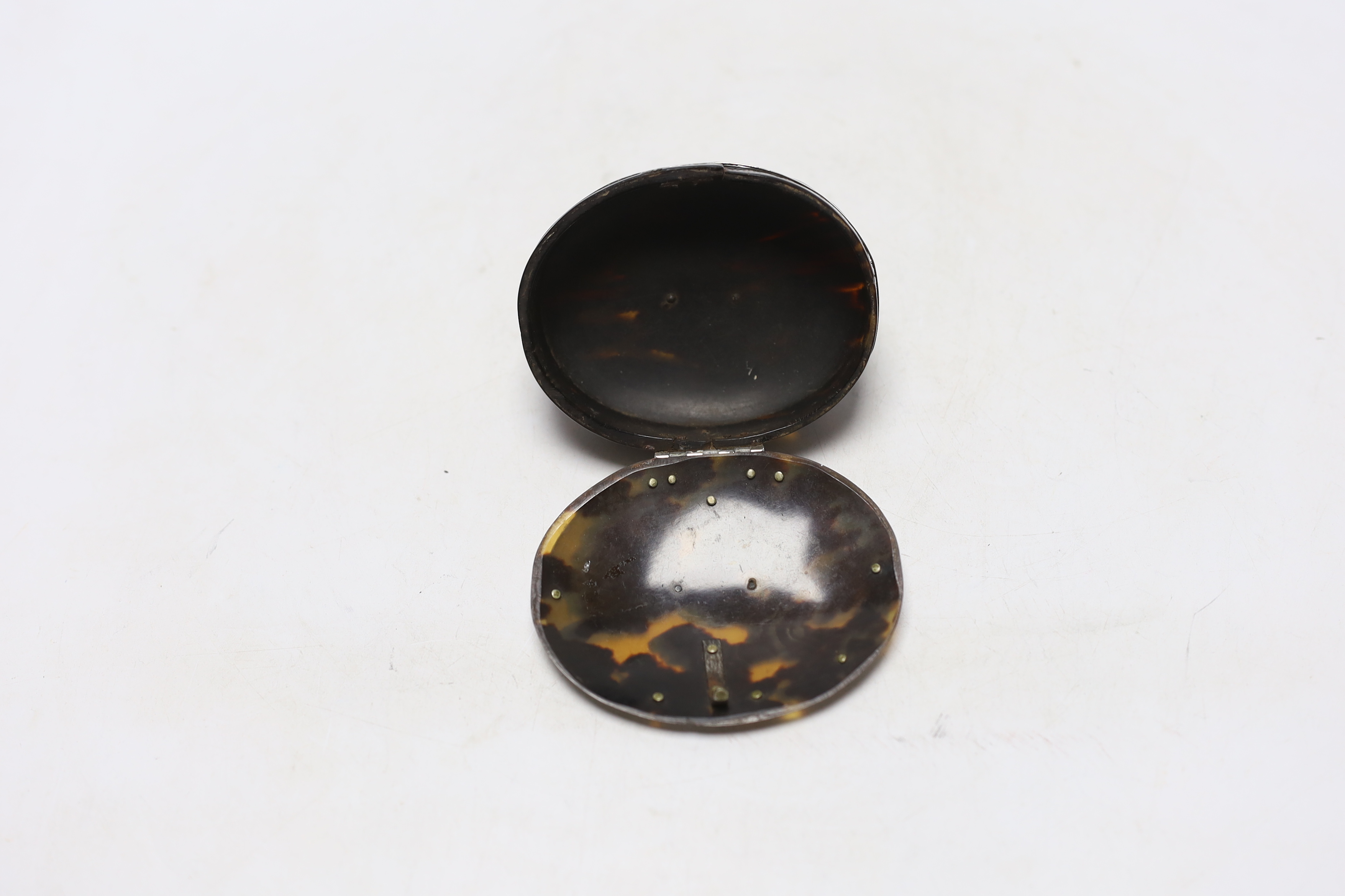 An early 19th century unmarked white metal mounted oval tortoiseshell snuff box, with fluted base, 92mm.